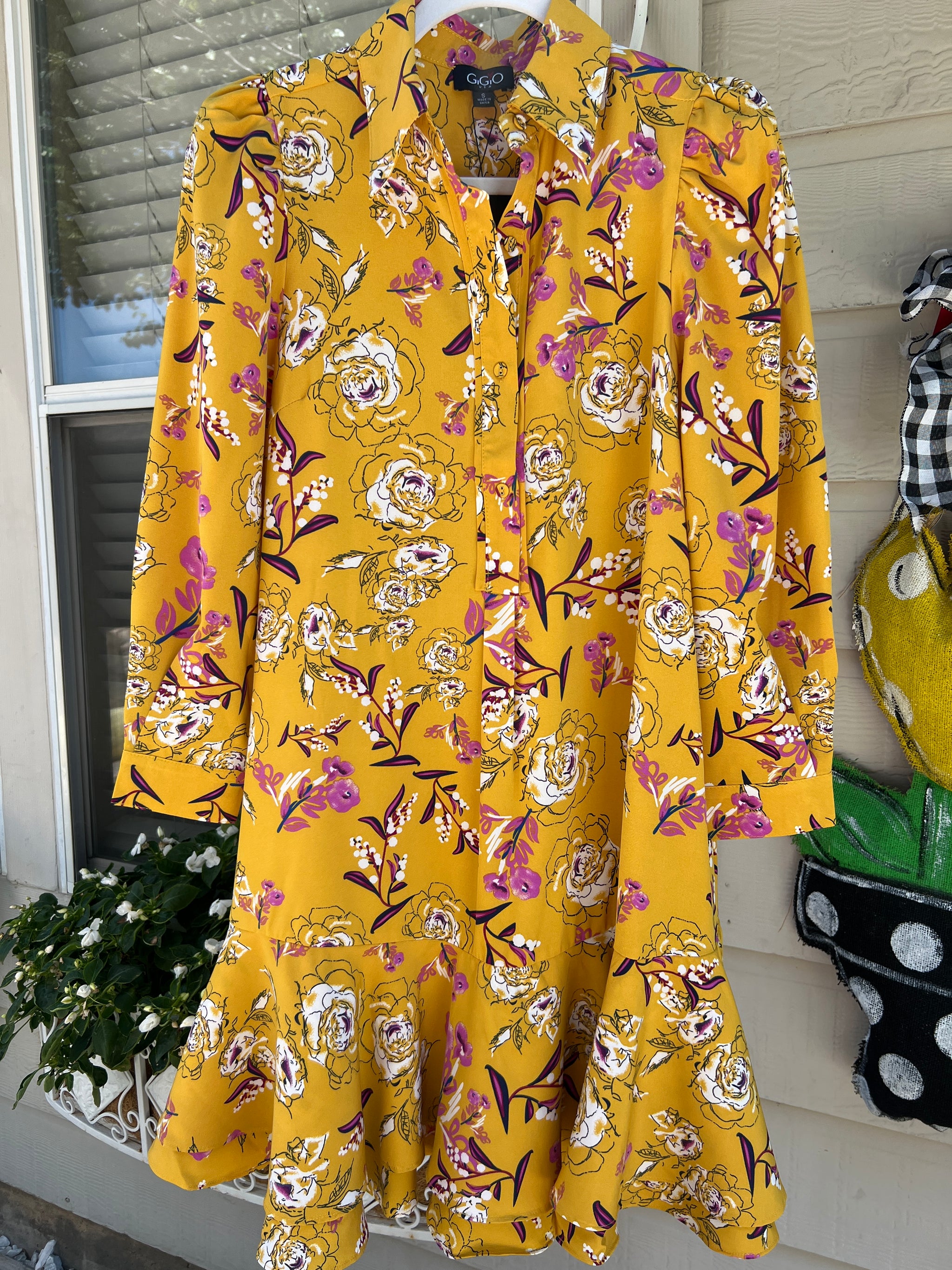 Yellow floral dress on a rack with a neutral background