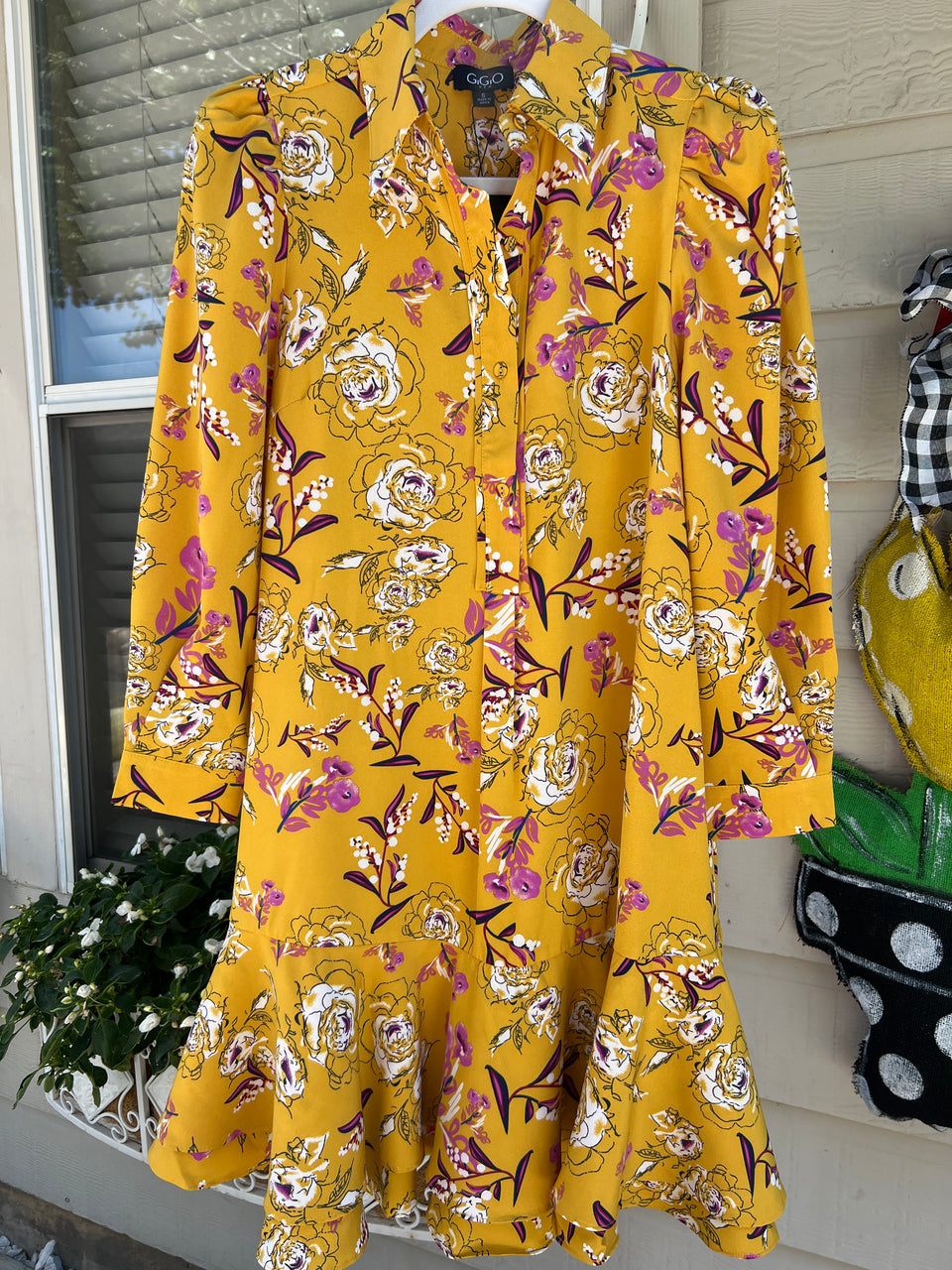 Yellow floral dress on a rack with a neutral background