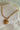Gold chain bracelet with a heart-shaped charm on a light stone background