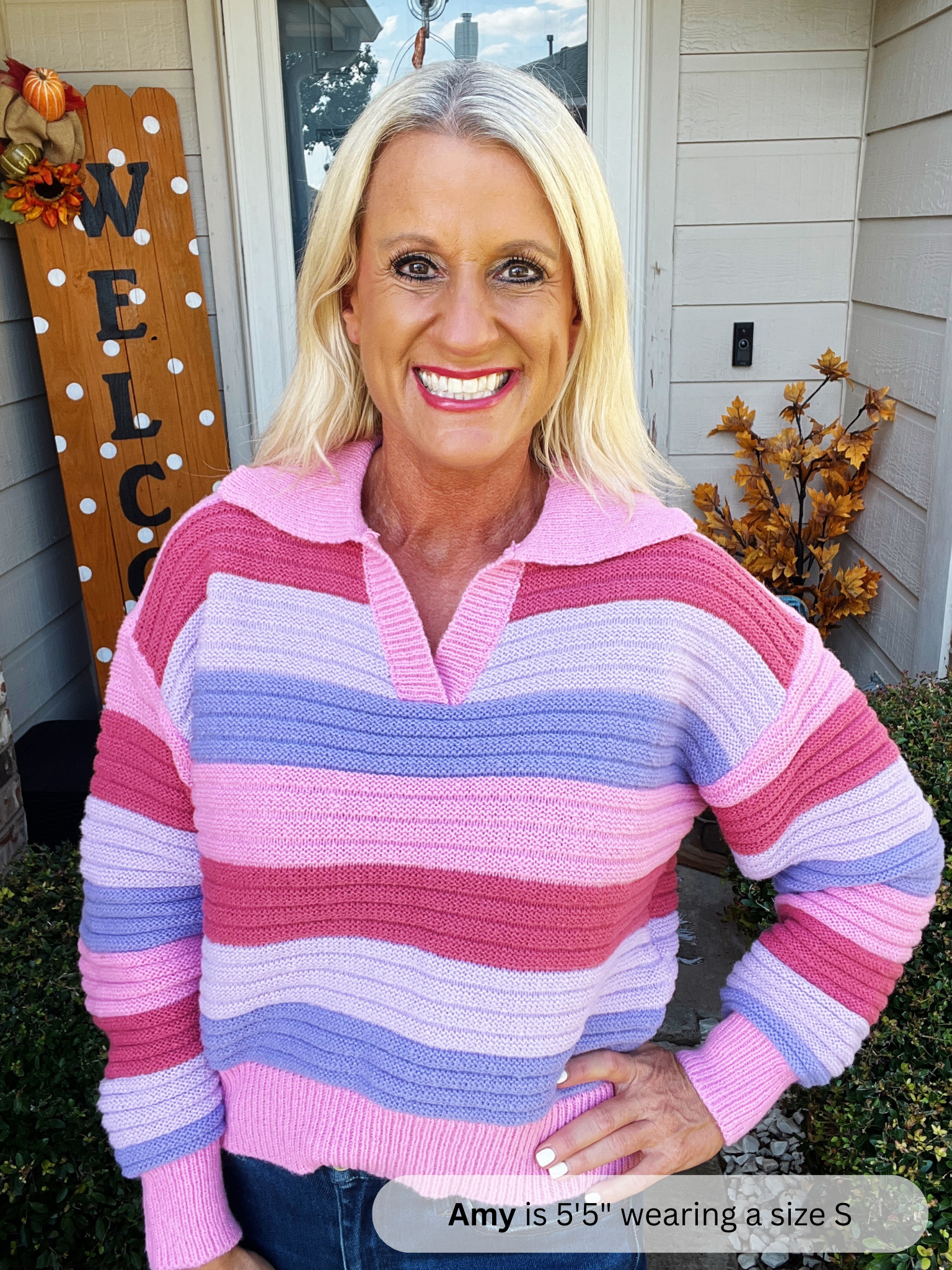Woman wearing a colorful striped sweater standing outside a house.